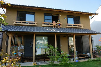 Diseño de fachada marrón tradicional pequeña de dos plantas con revestimiento de adobe y tejado a dos aguas