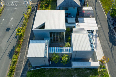 Exemple d'une façade de maison grise tendance à un étage avec un revêtement mixte, un toit en appentis et un toit en métal.