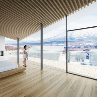 Diseño de dormitorio principal, contemporáneo, grande, con paredes blancas, suelo de madera en tonos medios, chimenea de doble cara, marco de chimenea de yeso y suelo beige