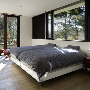 Immagine di una camera da letto contemporanea con pareti bianche, pavimento in legno verniciato e pavimento grigio