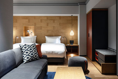 На фото: огромная гостевая спальня (комната для гостей) в скандинавском стиле с коричневыми стенами, светлым паркетным полом, коричневым полом, потолком с обоями и деревянными стенами без камина с