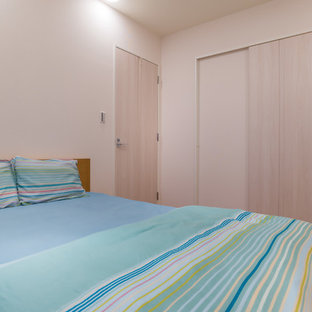 Imagen de dormitorio principal, nórdico, de tamaño medio, sin chimenea, con paredes blancas, suelo de contrachapado y suelo marrón