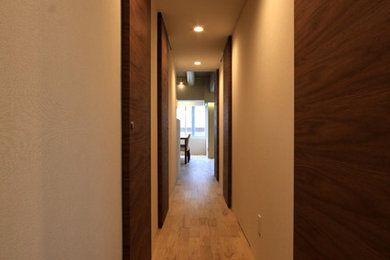 Modelo de recibidores y pasillos minimalistas con paredes blancas y suelo de madera en tonos medios