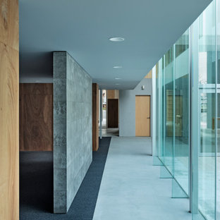 Inspiration pour un très grand couloir minimaliste avec un mur gris, béton au sol, un sol gris, un plafond en papier peint et du lambris.
