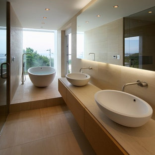 Foto di una stanza da bagno padronale moderna con ante lisce, ante in legno chiaro, vasca freestanding, pareti beige, lavabo a bacinella, top in legno e top beige