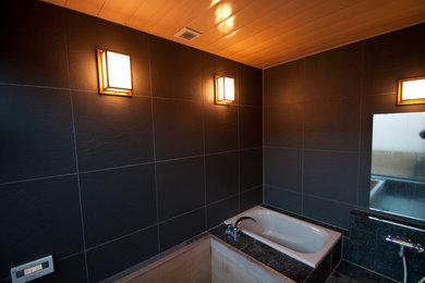 Diseño de cuarto de baño de estilo zen con bañera japonesa, paredes negras y suelo de mármol