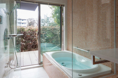 東京23区にあるコンテンポラリースタイルのおしゃれな浴室 (大型浴槽、オレンジのタイル、マルチカラーの壁) の写真