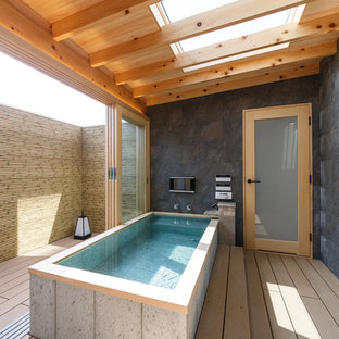 Immagine di una stanza da bagno etnica con vasca freestanding, pareti grigie e pavimento marrone
