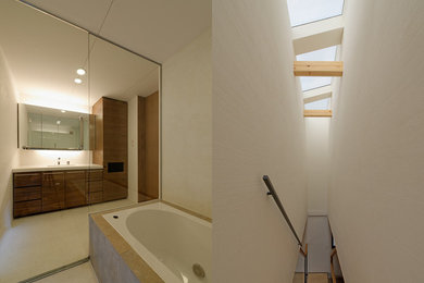 東京23区にあるコンテンポラリースタイルのおしゃれな浴室 (フラットパネル扉のキャビネット、濃色木目調キャビネット、ドロップイン型浴槽、ベージュの壁、コンクリートの床、アンダーカウンター洗面器、人工大理石カウンター、ベージュの床) の写真