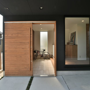 Cette photo montre une entrée asiatique avec un mur noir, une porte coulissante, une porte en bois clair et un sol gris.