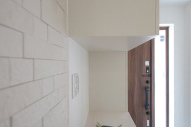 Стильный дизайн: прихожая с белыми стенами, одностворчатой входной дверью и входной дверью из дерева среднего тона - последний тренд