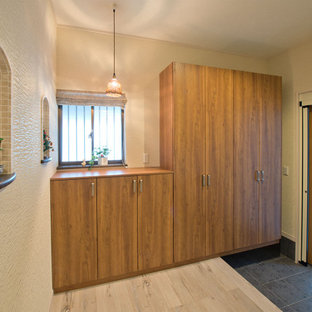 Inredning av en modern mellanstor hall, med vita väggar, ljust trägolv, en enkeldörr, metalldörr och beiget golv