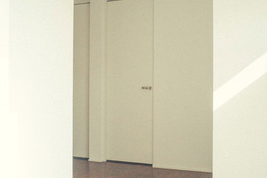 東京23区にある低価格の中くらいなモダンスタイルのおしゃれな玄関ホール (白い壁、濃色無垢フローリング、黒いドア) の写真