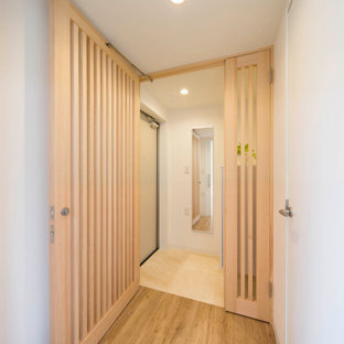 Réalisation d'une entrée nordique de taille moyenne avec un couloir, un mur blanc, béton au sol, une porte simple, une porte en bois brun, un sol gris, un plafond en papier peint et du papier peint.