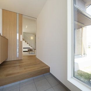 Réalisation d'une entrée minimaliste avec un couloir, un mur blanc, un sol en contreplaqué, une porte simple, une porte noire, un sol marron, un plafond en papier peint et du papier peint.