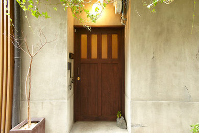 На фото: прихожая в восточном стиле с серыми стенами, бетонным полом, одностворчатой входной дверью и входной дверью из дерева среднего тона с