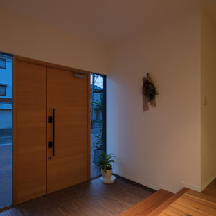 Aménagement d'un grand hall d'entrée moderne avec un mur blanc, un sol en contreplaqué, une porte double, une porte en bois brun et un sol marron.