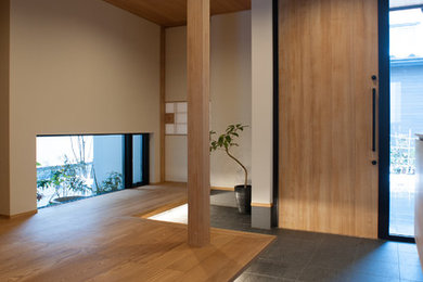 Modelo de hall asiático con paredes blancas, suelo de madera en tonos medios, puerta simple y puerta de madera en tonos medios
