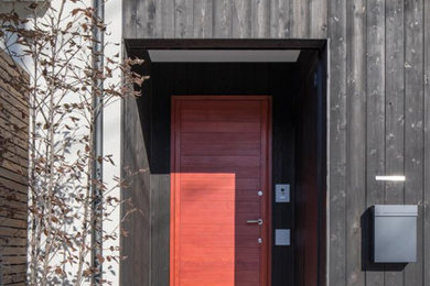 Ejemplo de puerta principal asiática de tamaño medio con paredes negras, suelo de cemento, puerta simple, puerta roja y suelo gris