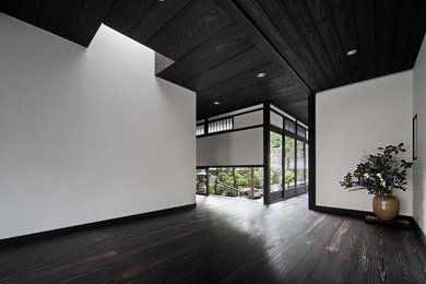 他の地域にある和風のおしゃれな玄関 (白い壁、濃色無垢フローリング、黒い床) の写真
