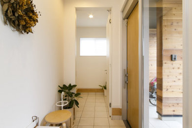 他の地域にあるおしゃれな玄関 (白い壁、合板フローリング、木目調のドア、茶色い床) の写真