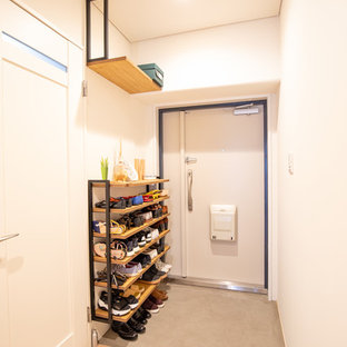 Idéer för en liten asiatisk hall, med vita väggar, betonggolv, en enkeldörr, en vit dörr och grått golv