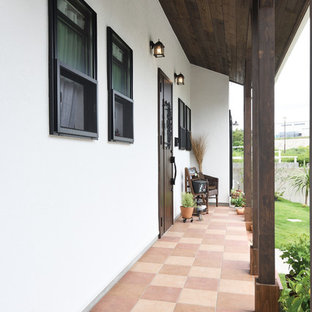 Foto di un grande portico etnico davanti casa con un portico chiuso, piastrelle e un tetto a sbalzo