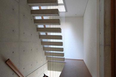 Imagen de escalera suspendida minimalista de tamaño medio sin contrahuella con escalones de hormigón y barandilla de madera