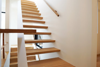 中くらいなコンテンポラリースタイルのおしゃれな階段 (木材の手すり) の写真