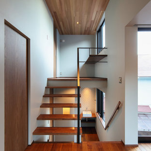 Ejemplo de escalera en U, de estilo zen, sin contrahuella, con escalones de madera y barandilla de metal