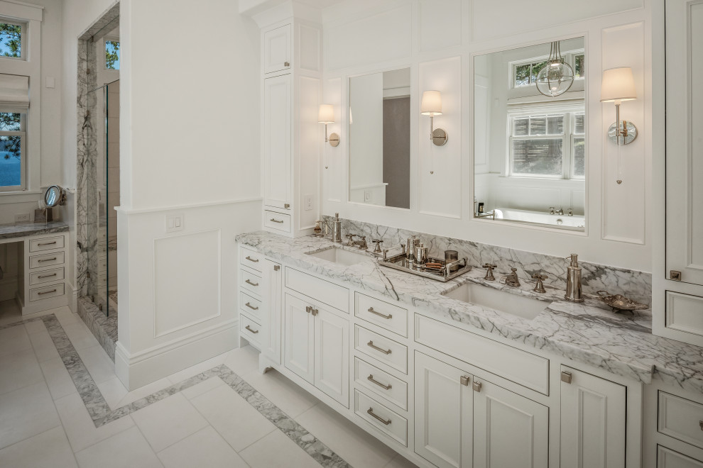 This is an example of an expansive transitional master bathroom in San Francisco with beaded inset cabinets, white cabinets, a freestanding tub, a double shower, a bidet, white tile, marble, white walls, marble floors, an undermount sink, marble benchtops, white floor, a hinged shower door, grey benchtops, an enclosed toilet, a double vanity, a built-in vanity and panelled walls.