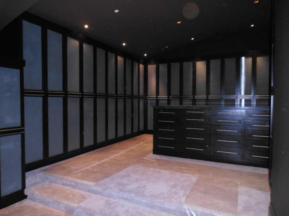This is an example of a traditional gender-neutral walk-in wardrobe in Las Vegas with dark wood cabinets and carpet.