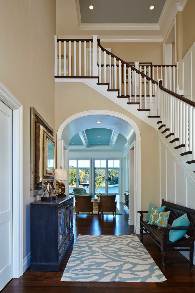 This is an example of a large beach style foyer in Miami with beige walls and dark hardwood floors.
