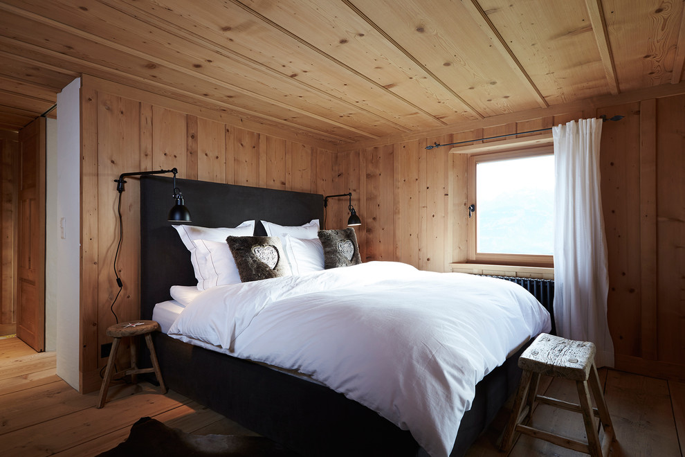 Photo of a country bedroom in Other with brown walls and medium hardwood floors.