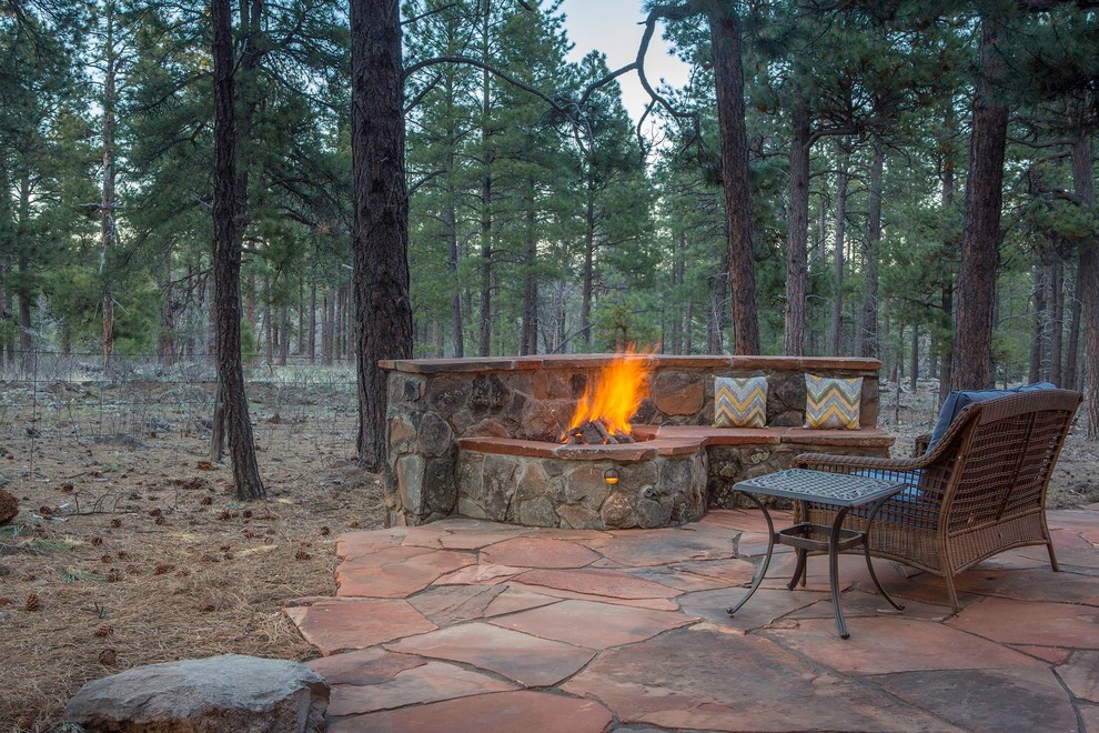 This is an example of a mid-sized country backyard patio in Phoenix with a fire feature, natural stone pavers and no cover.