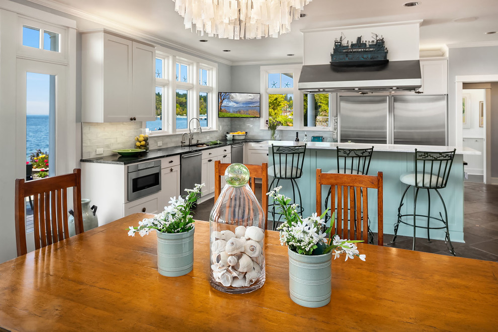 This is an example of a large beach style open plan kitchen in Seattle with an undermount sink, shaker cabinets, soapstone benchtops, glass tile splashback, stainless steel appliances, slate floors, with island, green floor and green benchtop.