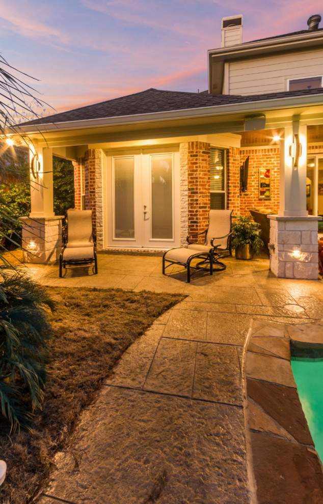 Inspiration for a mid-sized traditional backyard patio in Dallas with a fire feature, stamped concrete and a roof extension.