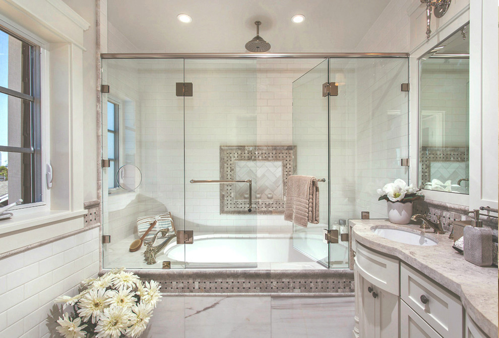 Inspiration for a large traditional master bathroom in San Diego with shaker cabinets, white cabinets, an alcove tub, a shower/bathtub combo, a two-piece toilet, white tile, subway tile, white walls, an undermount sink, limestone benchtops and a hinged shower door.