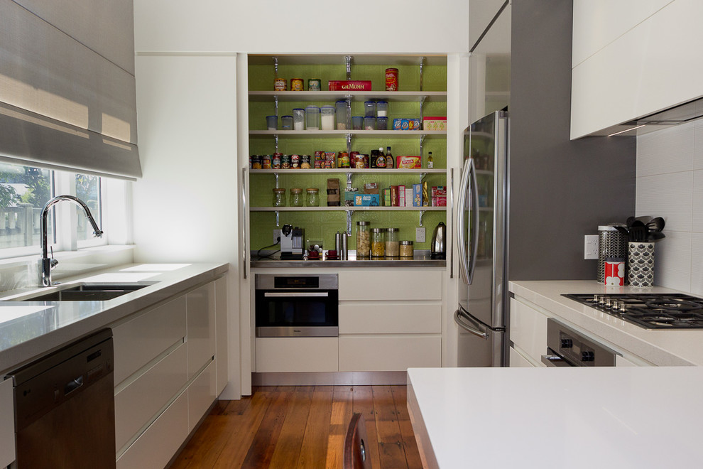 Photo of a mid-sized contemporary u-shaped kitchen pantry in Wellington with a double-bowl sink, flat-panel cabinets, white cabinets, quartzite benchtops, white splashback, ceramic splashback, stainless steel appliances and dark hardwood floors.