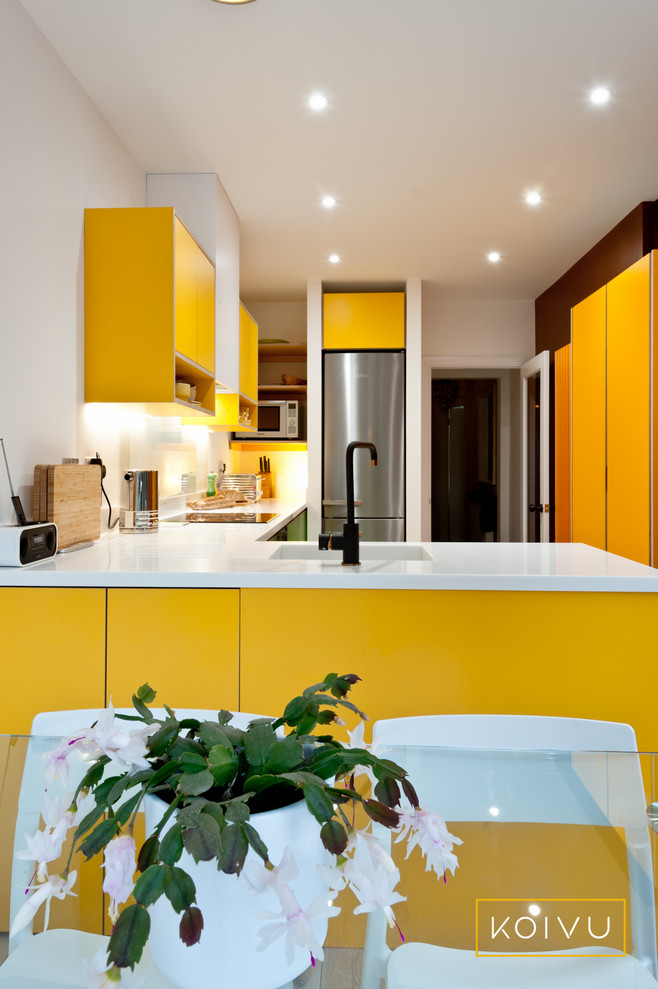Design ideas for a small contemporary l-shaped eat-in kitchen in Kent with an integrated sink, flat-panel cabinets, yellow cabinets, solid surface benchtops, white splashback, glass sheet splashback, stainless steel appliances, light hardwood floors, no island and white benchtop.