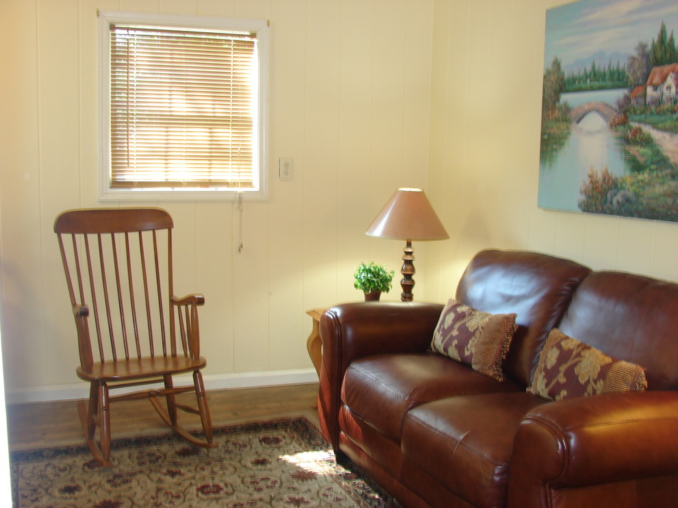 This is an example of a small country enclosed living room in Atlanta with beige walls and a concealed tv.