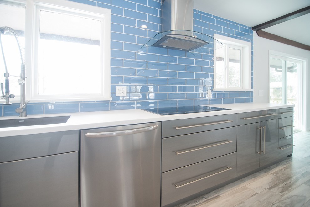 This is an example of a mid-sized modern l-shaped eat-in kitchen in Other with a single-bowl sink, blue splashback, glass tile splashback, stainless steel appliances, ceramic floors and with island.