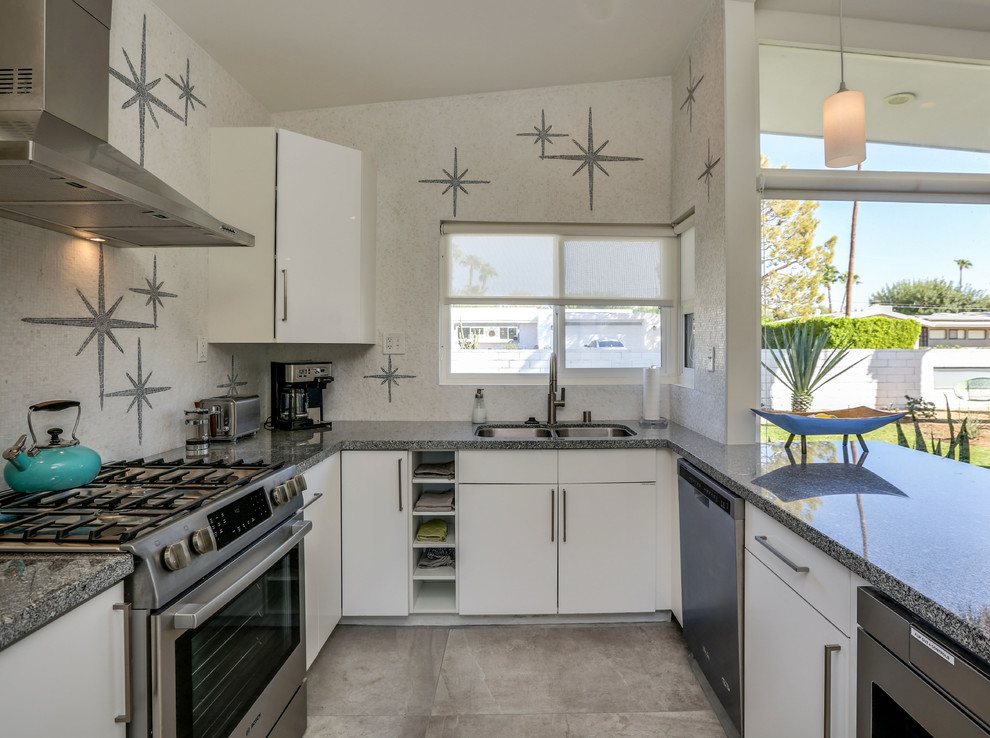 Photo of a medium sized midcentury u-shaped kitchen/diner in San Diego with a double-bowl sink, flat-panel cabinets, white cabinets, granite worktops, multi-coloured splashback, marble splashback, stainless steel appliances, porcelain flooring, a breakfast bar, grey floors and grey worktops.