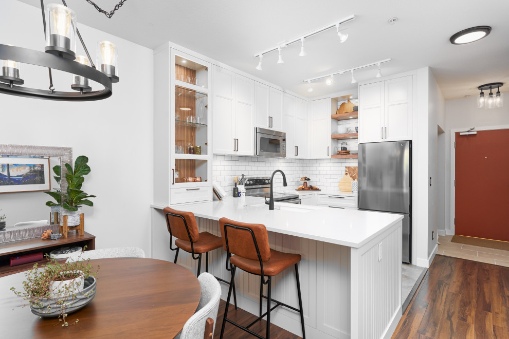 This is an example of a mid-sized contemporary u-shaped eat-in kitchen in Vancouver with an undermount sink, shaker cabinets, quartzite benchtops, white splashback, ceramic splashback, stainless steel appliances, ceramic floors and white benchtop.