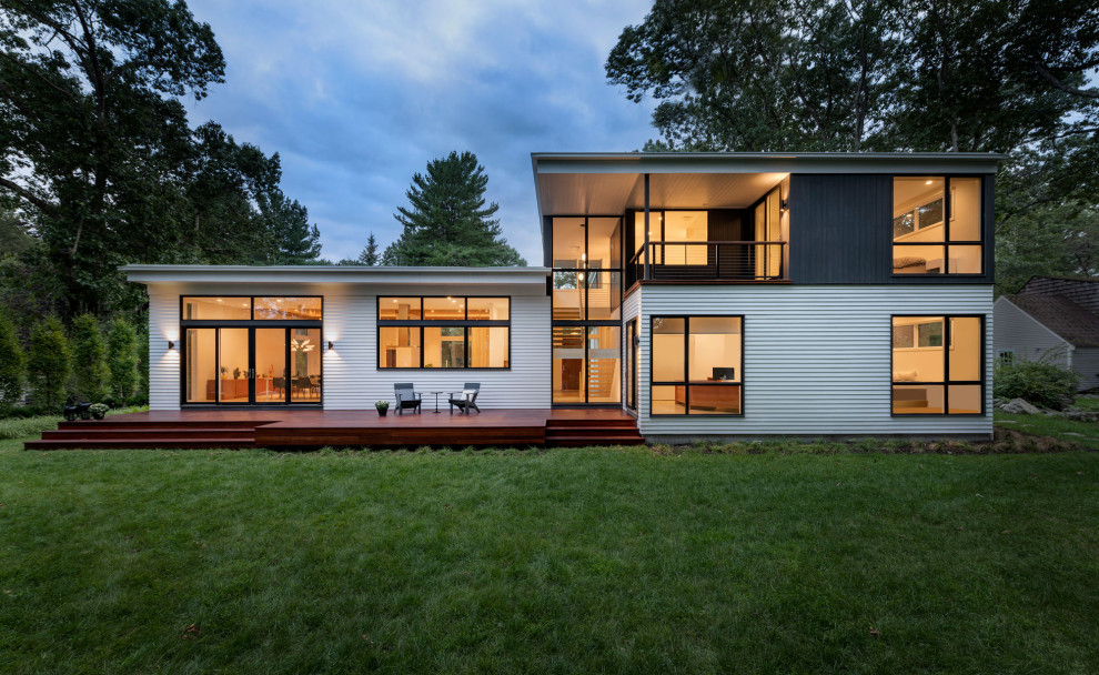 Стильный дизайн: двухэтажный, разноцветный частный загородный дом среднего размера в стиле ретро с плоской крышей и белой крышей - последний тренд