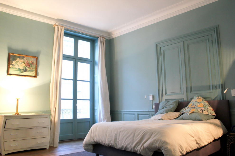 Geräumiges Klassisches Hauptschlafzimmer mit blauer Wandfarbe, vertäfelten Wänden, braunem Holzboden, Kamin, Kaminumrandung aus Stein, braunem Boden und Kassettendecke in Sonstige