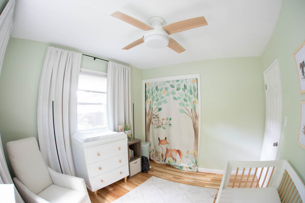 Cette image montre une petite chambre de bébé neutre design avec un mur vert et parquet clair.