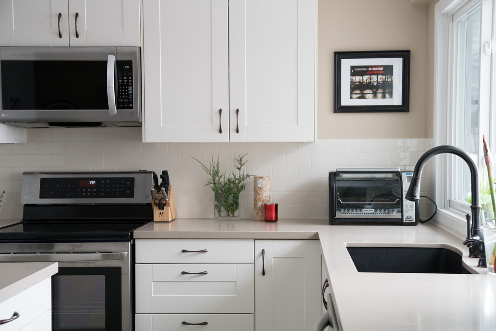 Transitional kitchen photo in Toronto with white cabinets and white backsplash