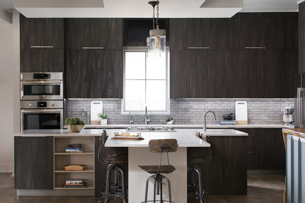 Photo of a contemporary l-shaped kitchen in Other with an integrated sink, flat-panel cabinets, black cabinets, grey splashback, subway tile splashback, stainless steel appliances, dark hardwood floors and with island.
