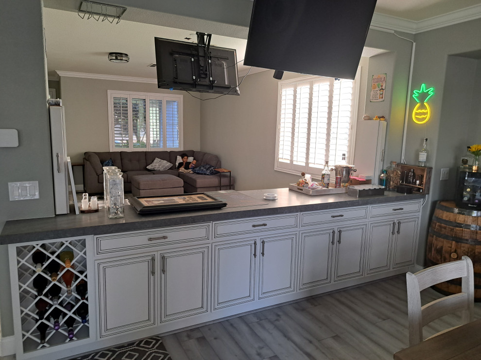 This is an example of a transitional home bar in Las Vegas with white cabinets, quartz benchtops, blue benchtop and recessed-panel cabinets.
